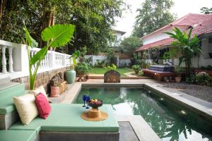 a swimming pool in a backyard with a bench and a table at Lamrin Ucassaim Goa An Indo Portuguese Hotel in Moira