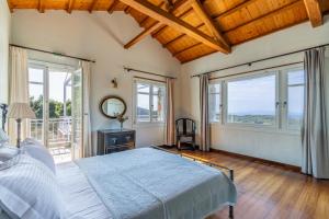 a bedroom with a bed and large windows at Villa Salkim in Skopelos Town