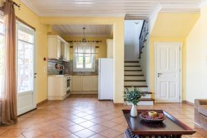 a kitchen with yellow walls and a table and a refrigerator at Villa Salkim in Skopelos Town