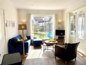 a living room with a blue couch and a table at Holiday home Zeeroos in Koudekerke
