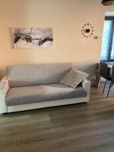 a couch in a living room with a clock on the wall at Casa Vacanze Spolina Cossato BI in Cossato