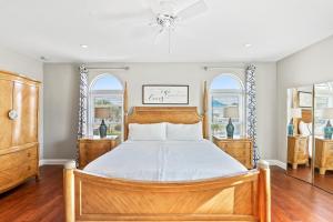 a bedroom with a wooden bed and two windows at Oceanview Family & Pet-Friendly Escape, 300 Steps to Beach, 2608H in New Smyrna Beach