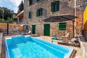 a swimming pool with an umbrella next to a building at Stone Two Bedroom Villa with Pool in Staševica