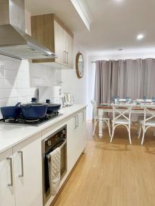 a kitchen with white cabinets and a table with chairs at Cloverton Escape Retreat in Kalkallo