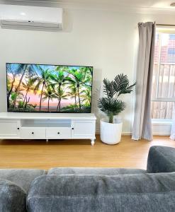 a living room with a couch and a flat screen tv at Cloverton Escape Retreat in Kalkallo