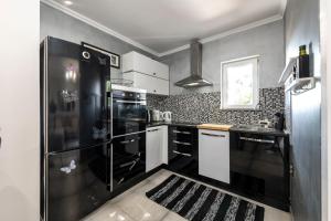 ムリニにあるVilla Nedia - 2 Apartments with Private Pool & Sea Viewのキッチン(黒い冷蔵庫、白いキャビネット付)