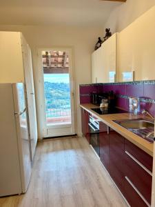 a kitchen with purple walls and a large window at Magnifique Studio Cagnes Sur Mer in Cagnes-sur-Mer