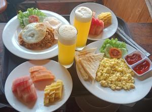 a table with three plates of food and two glasses of beer at JinengBali Eco Lodge in Tegalalang
