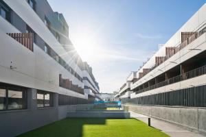 ein leerer Innenhof eines Gebäudes mit grünem Gras in der Unterkunft apartamentos con piscina de invierno y garaje ALQUILER TEMPORAL in San Sebastián de los Reyes