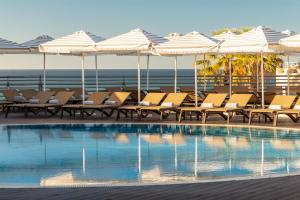 a swimming pool with chairs and umbrellas and the ocean at Grande Real Santa Eulalia Resort & Hotel Spa in Albufeira +112 photos