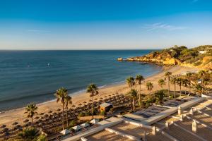 a beach with chairs and palm trees and the ocean at Grande Real Santa Eulalia Resort & Hotel Spa in Albufeira