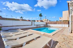 a swimming pool with chaise lounges next to a building at Villa Martin in Portocolom