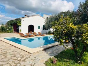 een zwembad met ligstoelen en een huis bij Villa Es Puig, piscina y vistas a la montaña in Santa Margalida