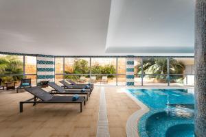 a pool with a row of chaise lounges and a swimming pool at Grande Real Santa Eulalia Resort & Hotel Spa in Albufeira