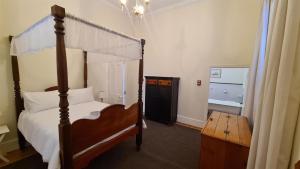 a bedroom with a canopy bed and a wooden table at De Kothuize 2 in Graaff-Reinet