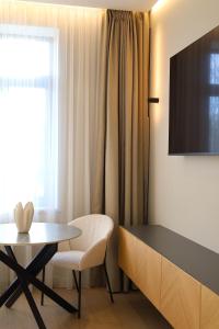 Zimmer mit einem Tisch, einem Stuhl und einem TV in der Unterkunft Memel Town Apartments in Klaipėda