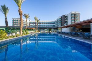 a swimming pool with palm trees and a building at Sural Saray Hotel in Side