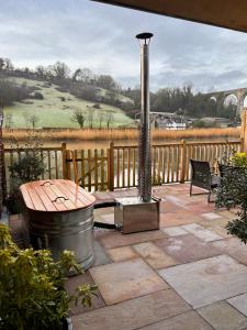 a patio with a grill and a wooden fence at Viaduct River View & Outdoor Bath - Couples Retreat in Calstock