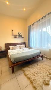 a bedroom with a bed and a window with a rug at Lush Urbarn Oasis in Kampala