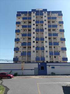 a large apartment building with blue balconies in a parking lot at Quarto Residencial Dubai - Lazer Completo in Brasília