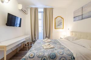 a bedroom with a bed with a desk and a television at Elephant's Smile B&B in Catania