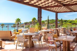 an outdoor patio with tables and chairs and the ocean at Grande Real Santa Eulalia Resort & Hotel Spa in Albufeira