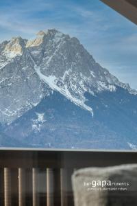 een raam met uitzicht op een met sneeuw bedekte berg bij BergVibes in Garmisch-Partenkirchen