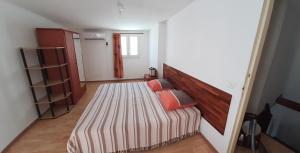 een kleine slaapkamer met een bed met een houten hoofdeinde bij Appartement LONGANIS in Saint-Gilles-les-Bains