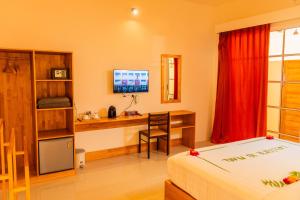 a bedroom with a bed and a desk with a computer at Pearl Dhigurah in Dhigurah
