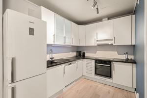 a white kitchen with white cabinets and appliances at Family Friendly - Modern - City Central in Bergen