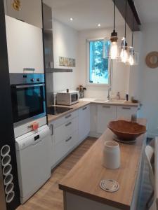 une cuisine avec des armoires blanches et une table en bois dans l'établissement La Maison du Clocher, à Rivedoux-Plage