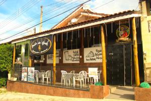 un restaurant avec des chaises blanches en face d'un bâtiment dans l'établissement Pousada São Judas Tadeu, à Cachoeira Paulista