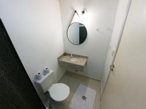une salle de bain avec des toilettes blanches et un miroir dans l'établissement Pousada São Judas Tadeu, à Cachoeira Paulista