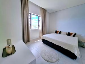 Soleia 2 - Pereybere - Appartement Cozy avec piscine proche plage في غراند بايَ: غرفة نوم بيضاء مع سرير ونافذة