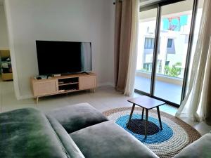 Soleia 2 - Pereybere - Appartement Cozy avec piscine proche plage في غراند بايَ: غرفة معيشة مع أريكة وتلفزيون بشاشة مسطحة