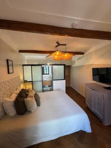 una camera da letto con un grande letto bianco e una televisione di Maison Louisa a Saint-Paul-de-Vence