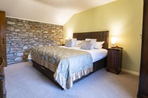 a bedroom with a large bed and a stone wall at Theaked Stones in Leyburn