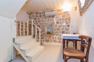 Habitación con pared de piedra, escaleras y mesa. en Peti Apartment, en Dubrovnik