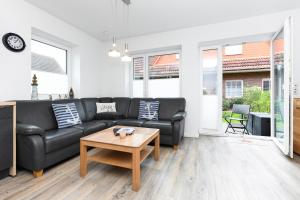 een woonkamer met een zwarte bank en een tafel bij Ferienhaus Lüttje Krabbe in Carolinensiel