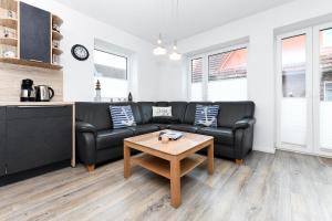 een woonkamer met een zwarte bank en een tafel bij Ferienhaus Lüttje Krabbe in Carolinensiel