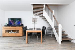een eetkamer met een tafel en een trap bij Ferienhaus Lüttje Krabbe in Carolinensiel +45 foto's