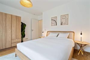 阿尔泽特河畔埃施A Stylish Retreat in Esch Urban Landscape的卧室里有一张白色的床和一个木柜