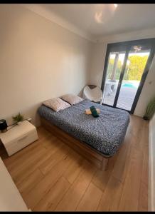 een slaapkamer met een bed en een groot raam bij Bel appartement avec piscine privative à 150m de la plage 6 couchages in Le Barcarès