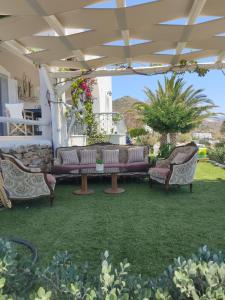 a patio with couches and chairs on the grass at Zephyrus Sunset House. Amazing View and Privacy! in Agkidia