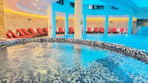 Hotel Orpheus - Casino and SPA في بامبوروفو: مسبح كبير وكراسي حمراء في مبنى