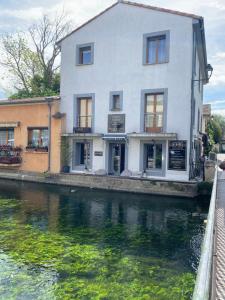a white building on the side of a river at Olive- Vaste appartement donnant sur la Sorgue in LʼIsle-sur-la-Sorgue