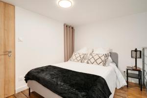 a white bedroom with a black blanket on a bed at L'Eden d'Elyse - Duplex premium- parking gratuit in Nancy