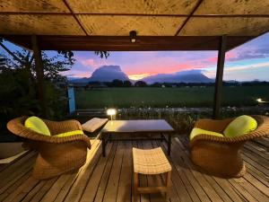 - une terrasse en bois avec des chaises, une table et un coucher de soleil dans l'établissement Khampanna Cafe' resort & Nature, à Ban Sop Nong 2 autres photos