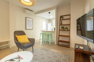 a living room with a tv and a chair and a table at Charming Apartment with private patio at Plaza de España by OCityzen in Seville