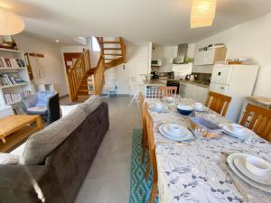 ein Esszimmer und eine Küche mit einem Tisch und einem Sofa in der Unterkunft MASSALINE - Jardin clos, Plage 1km - K38 in Carnac
